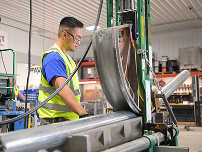 In house team member working on a large machine bending steel